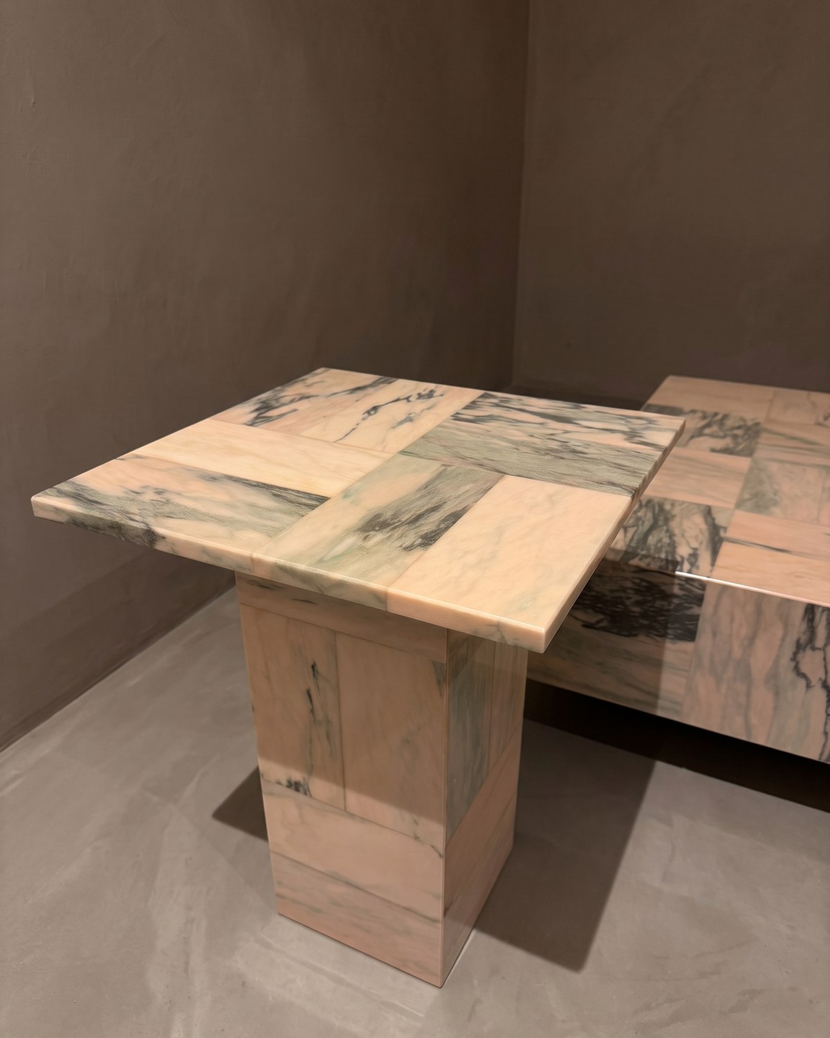 The La Rosa side table — a square woven top on a stone pedestal, the coffee table behind